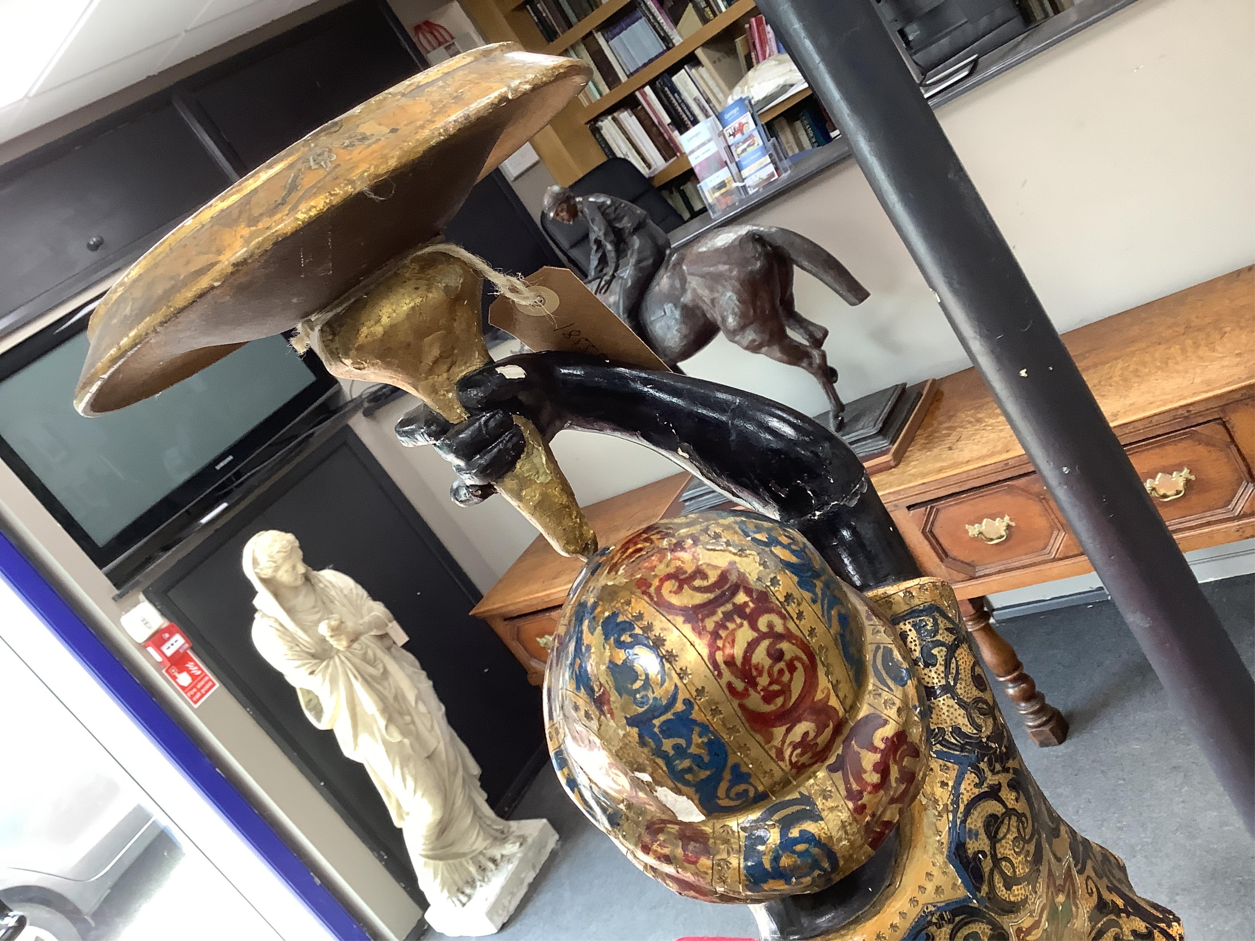 A 19th century Italian carved wood and composition polychrome painted blackamoor torchere, modelled standing with one arm holding a scroll pillar on waisted circular base and lions paw feet, 106cm high